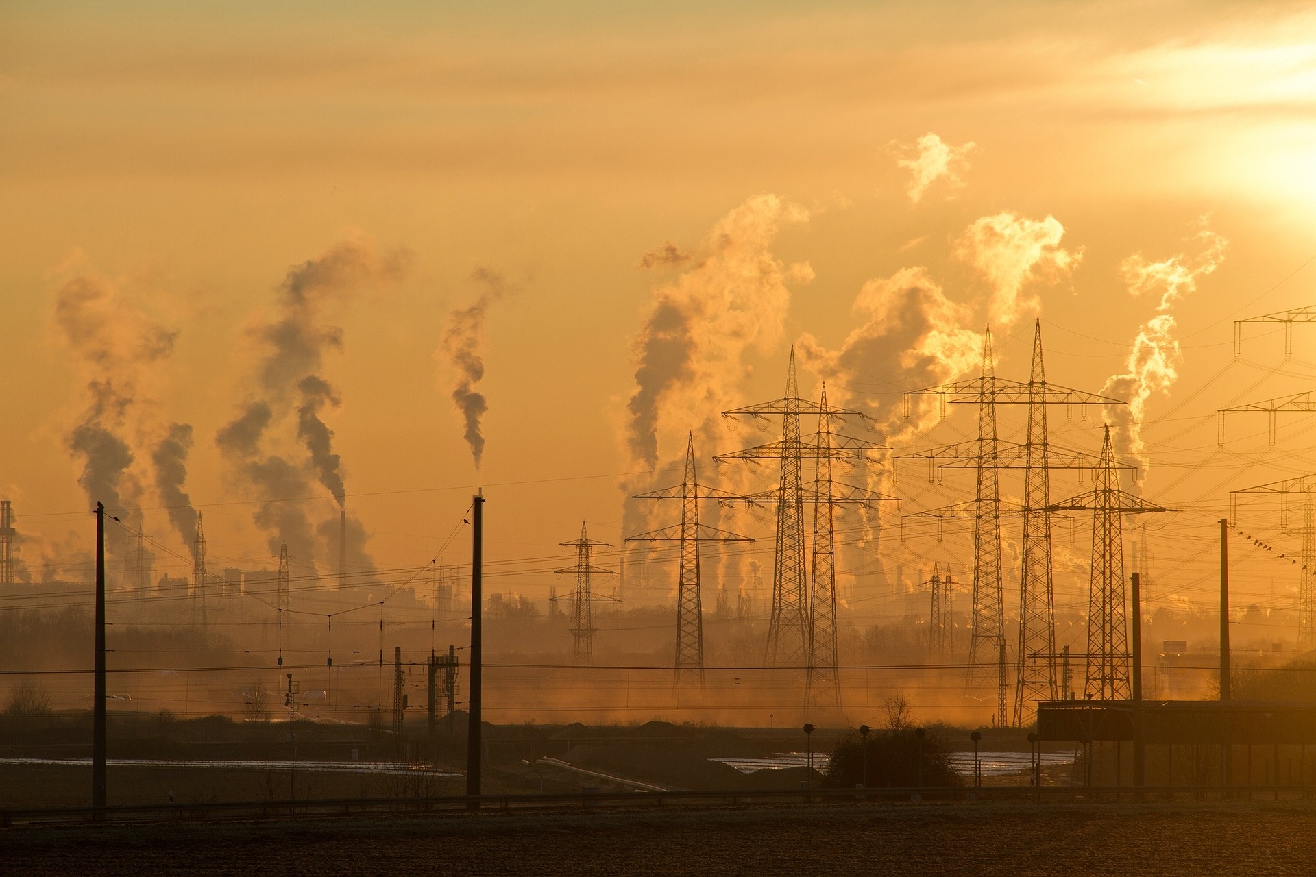 Industrial smokestacks emitting pollution under cloudy skies, highlighting environmental risks to children's health.