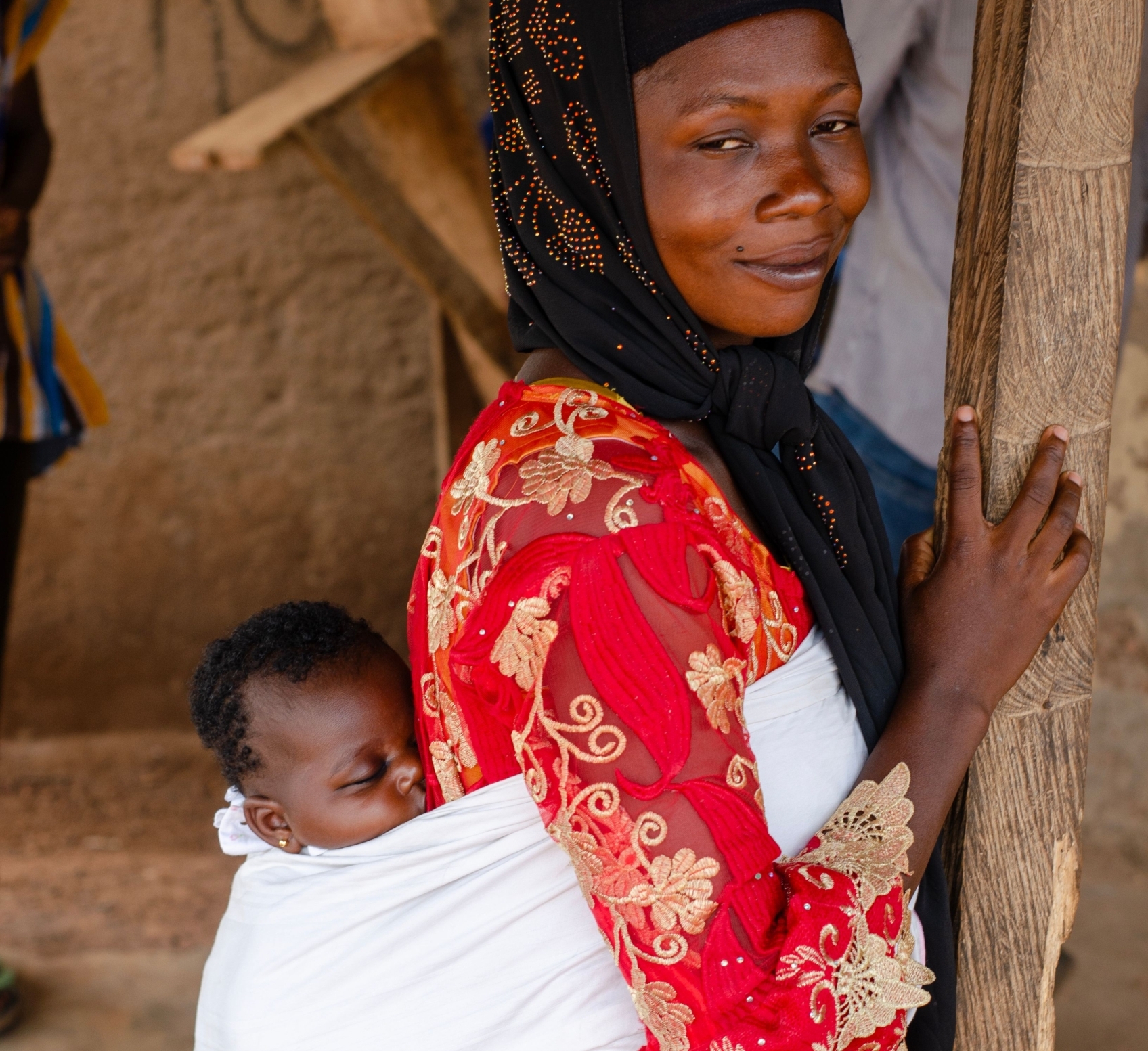 A woman in traditional attire holds her newborn baby lovingly. Maternal And Newborn Care in Mali