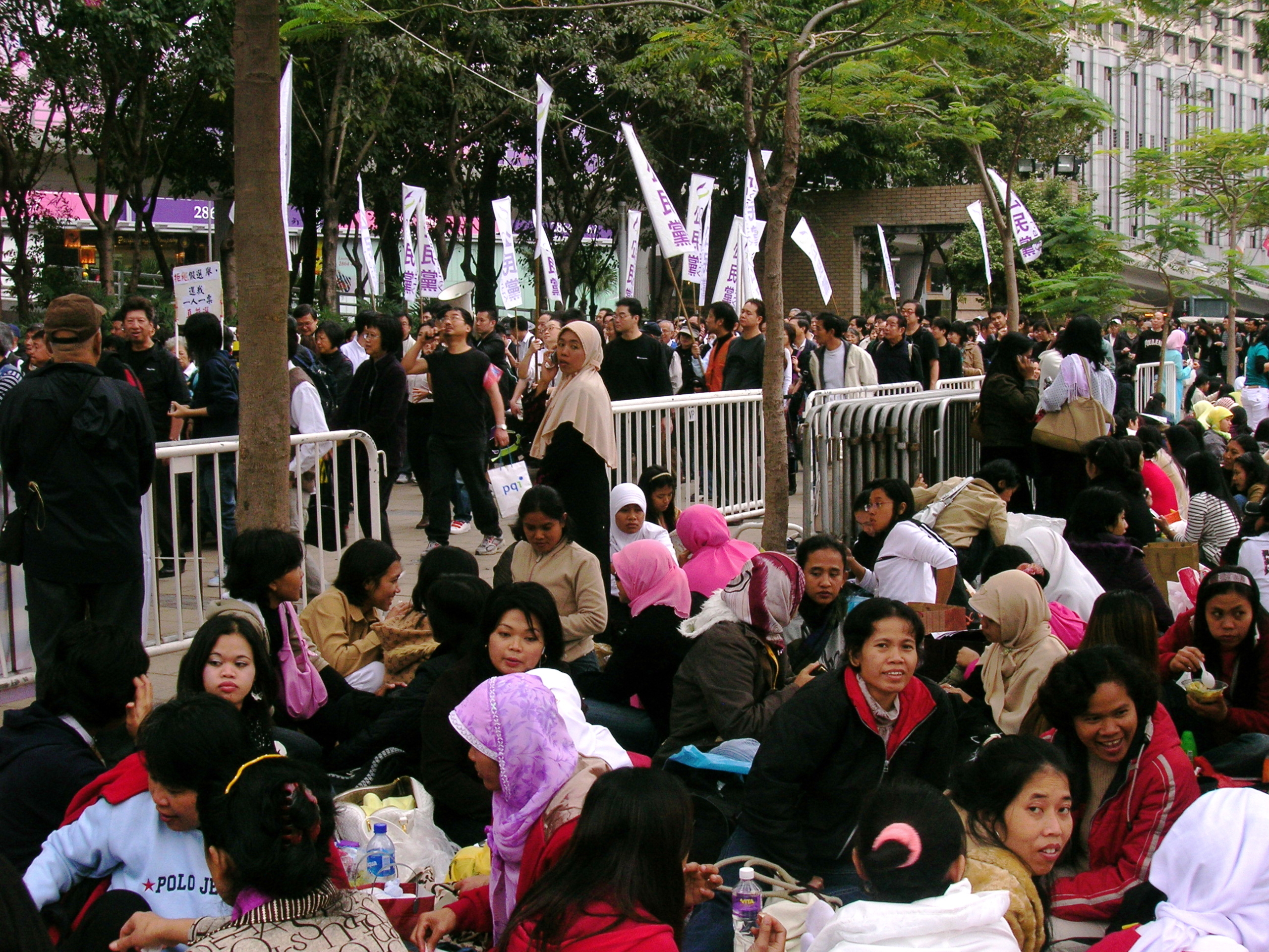 Indonesian domestic workers relaxing in a Hong Kong park, seated together. Hong Kong's Migrant Domestic Workers