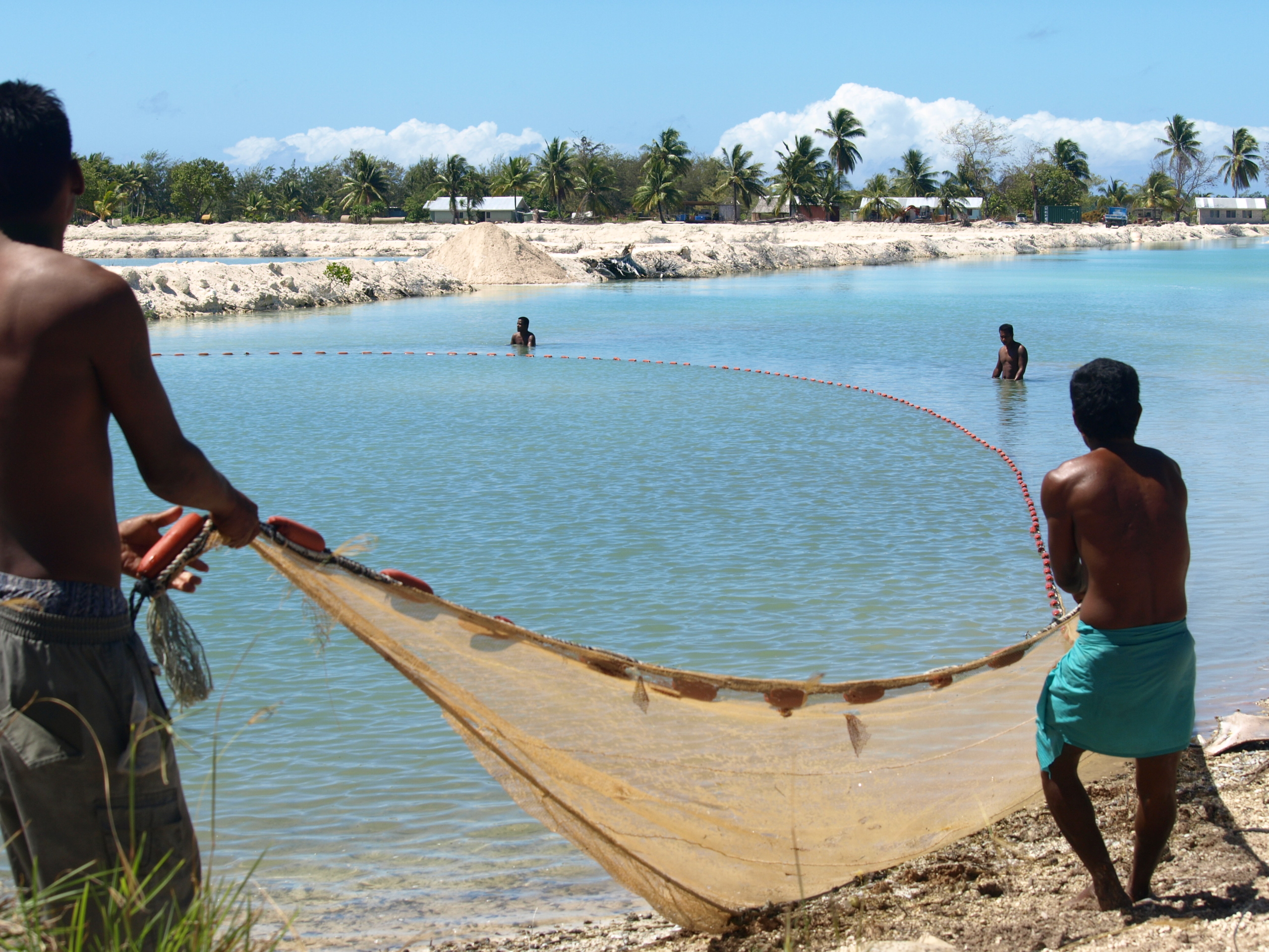Fisherman casting net in Kiribati waters, showcasing local poverty reduction efforts. poverty reduction in Kiribati