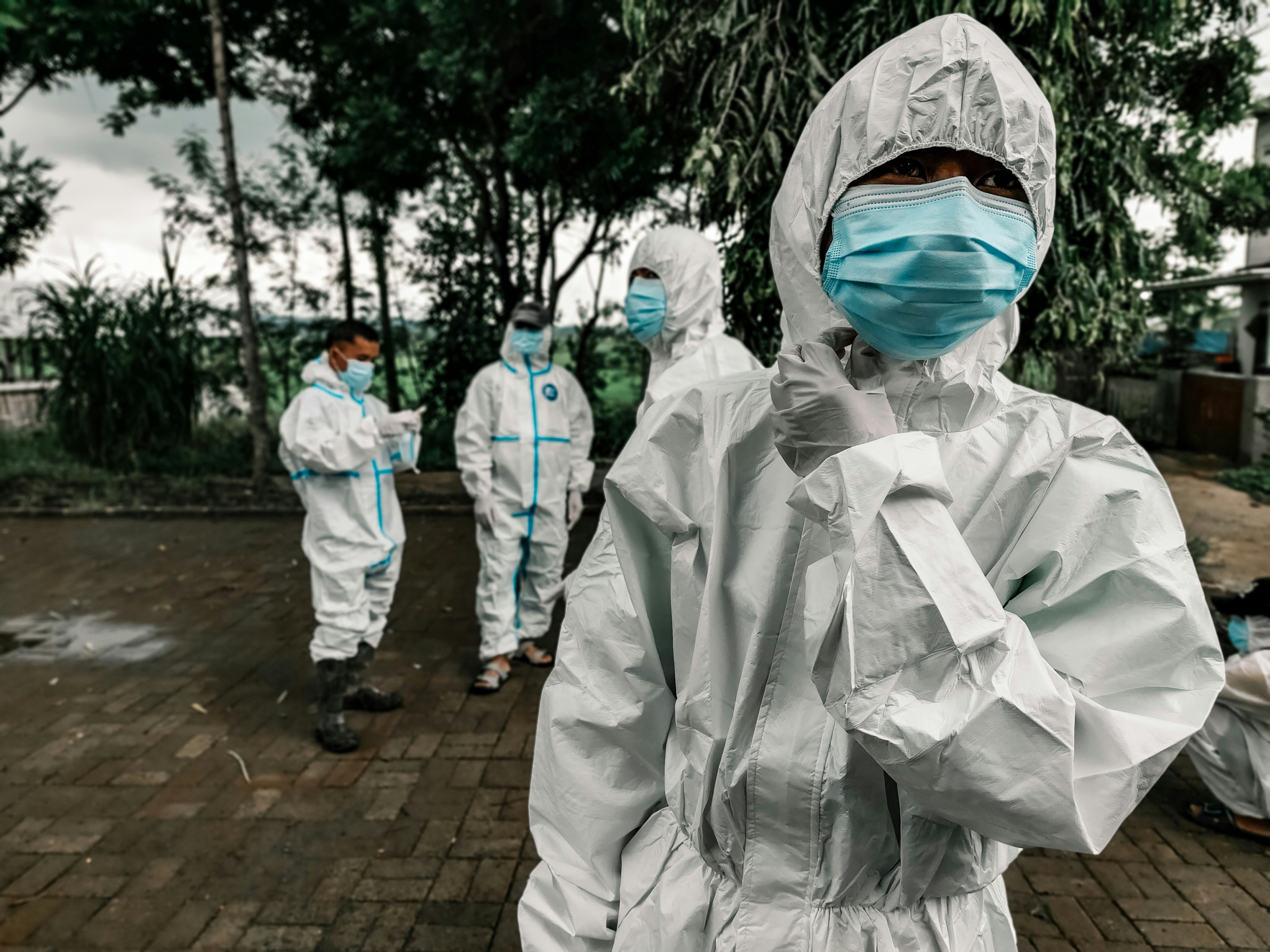 Health workers in protective gear walking on a street, highlighting USAID cuts impact on Ebola response. Ebola Outbreak in the DRC