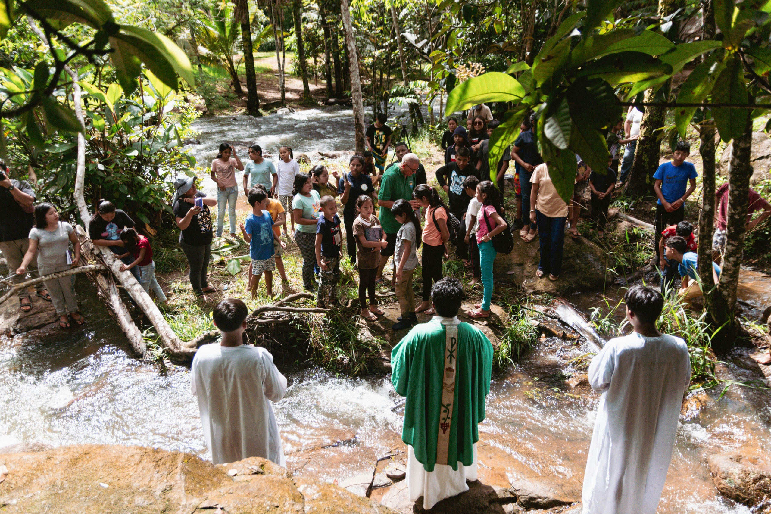 Priests baptizing people in a river, highlighting cultural aspects amid poverty in Guyana.