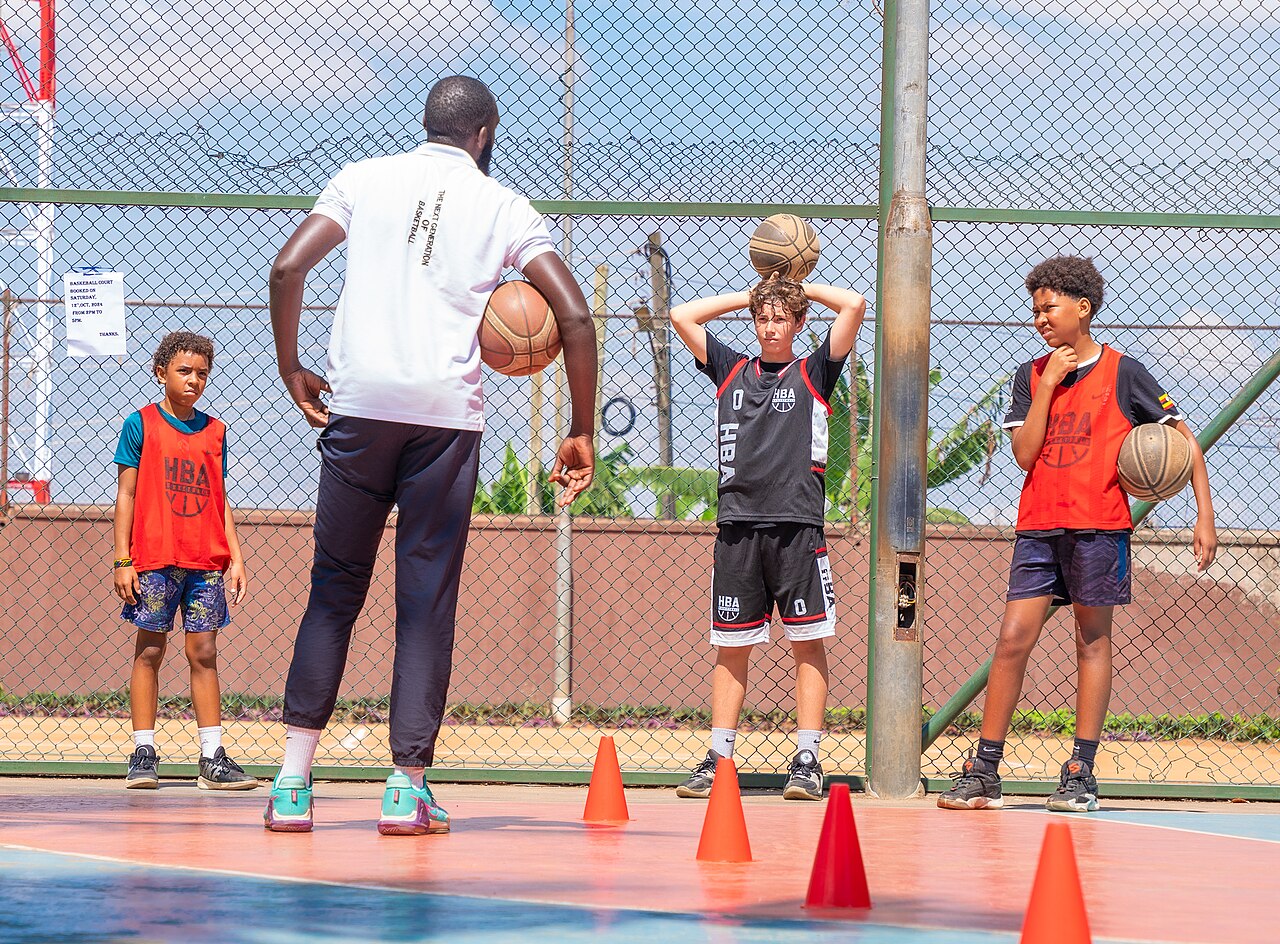 Children playing basketball in a gym, part of sports programs fighting poverty.