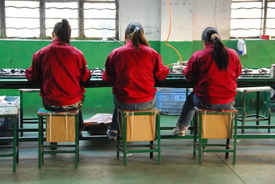 Factory workers in China assembling electronics at a production line in a factory.