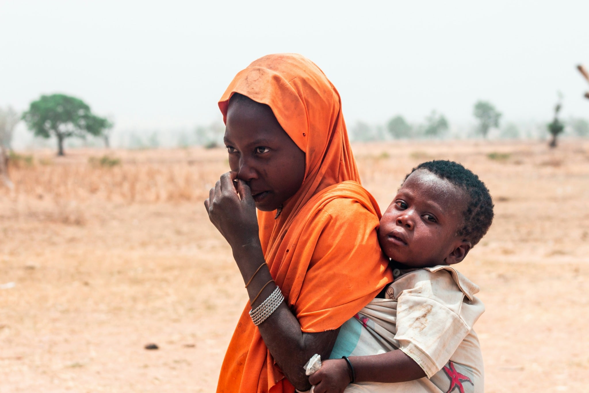 A person in orange carrying a child